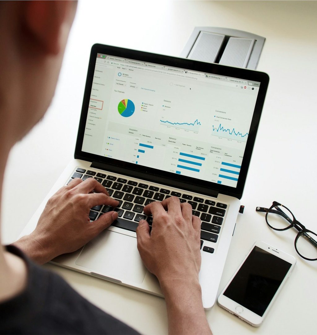 Michelle Bechstein-Ferenz - MBF-Marketing - Social-Media Managerin für KMU Person arbeitet an einem Laptop mit Datenanalysen, daneben ein Smartphone und eine Brille.